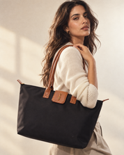 rie uma imagem editorial fashion para a Urbanna com o produto anexado. Assuma a direção criativa: escolha a cena, iluminação, paleta, enquadramento e presença ou não de modelo conforme o estilo do produto. @Bolsa Shopper Santa Lolla Preta Nylon Detalhe Caramelo